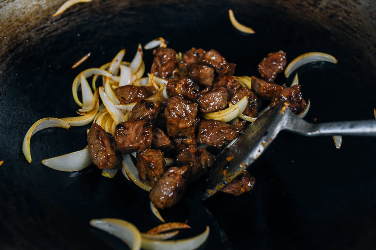 adding beef back to onions in wok