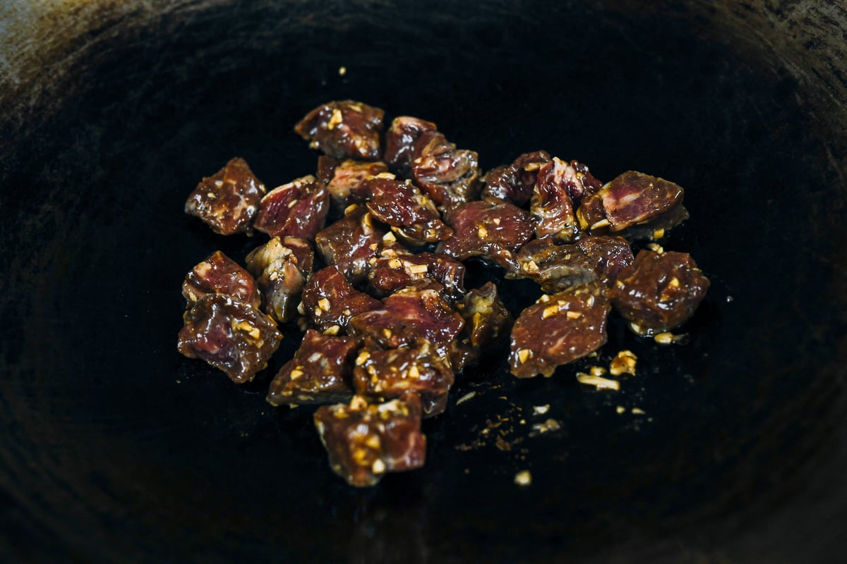 searing marinated steak cubes in wok