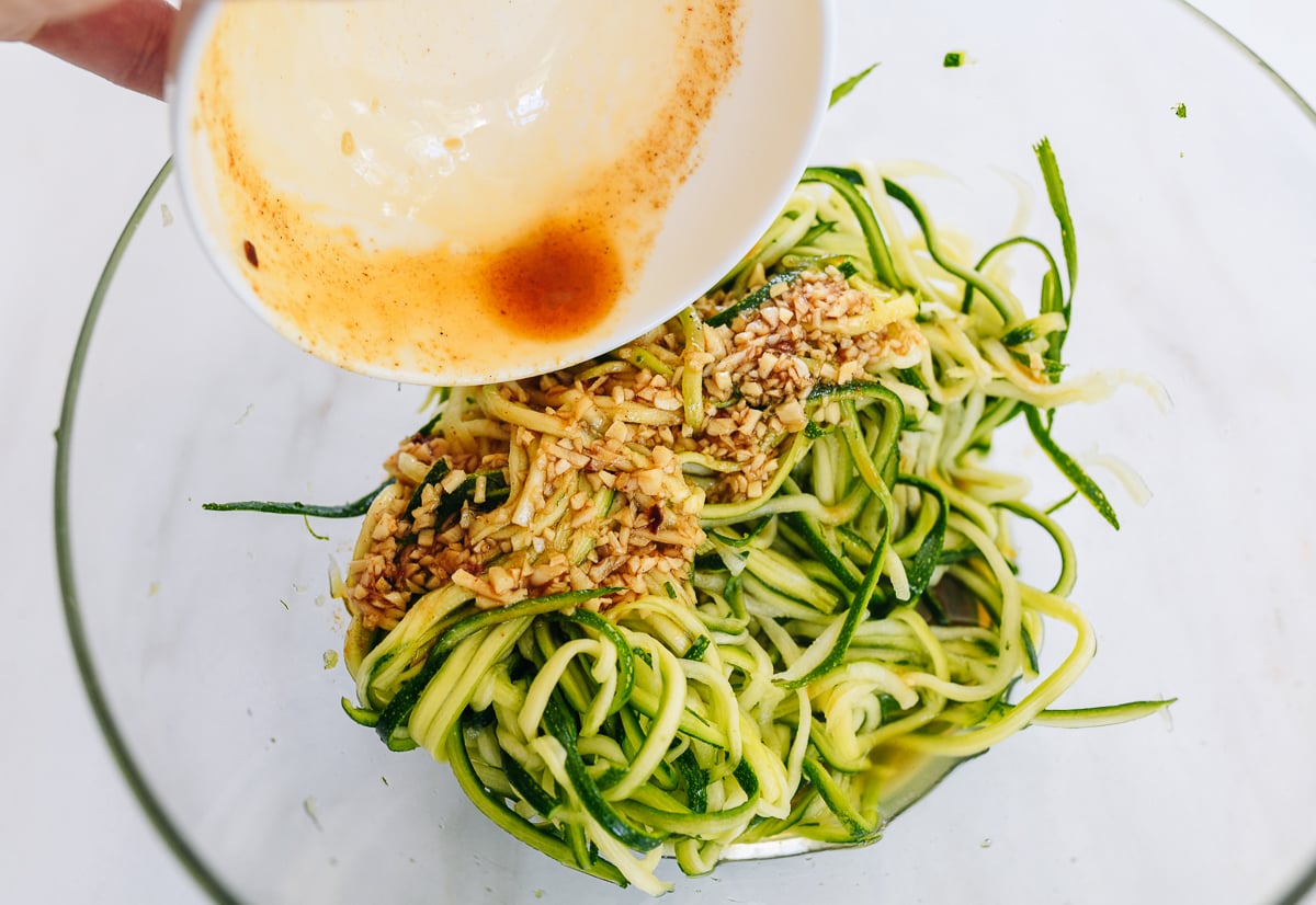 adding dressing to salted julienned zucchini