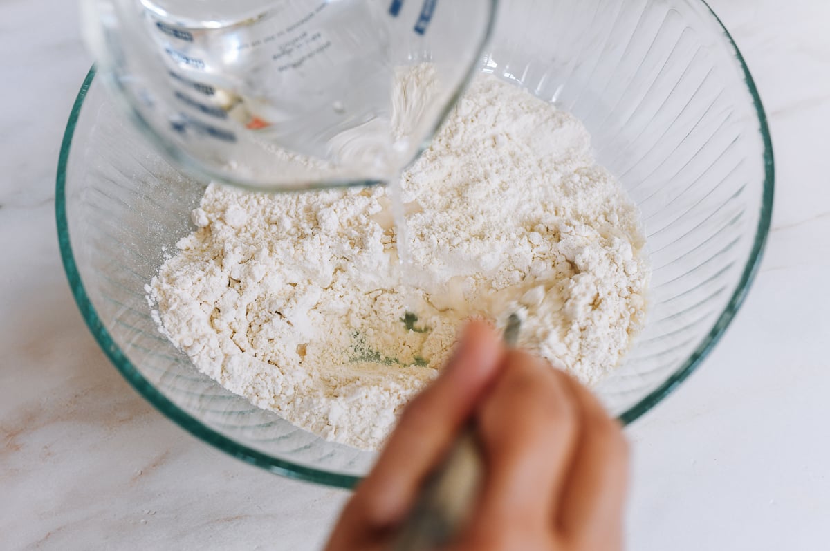 adding boiling water to flour in glass mixing bowl