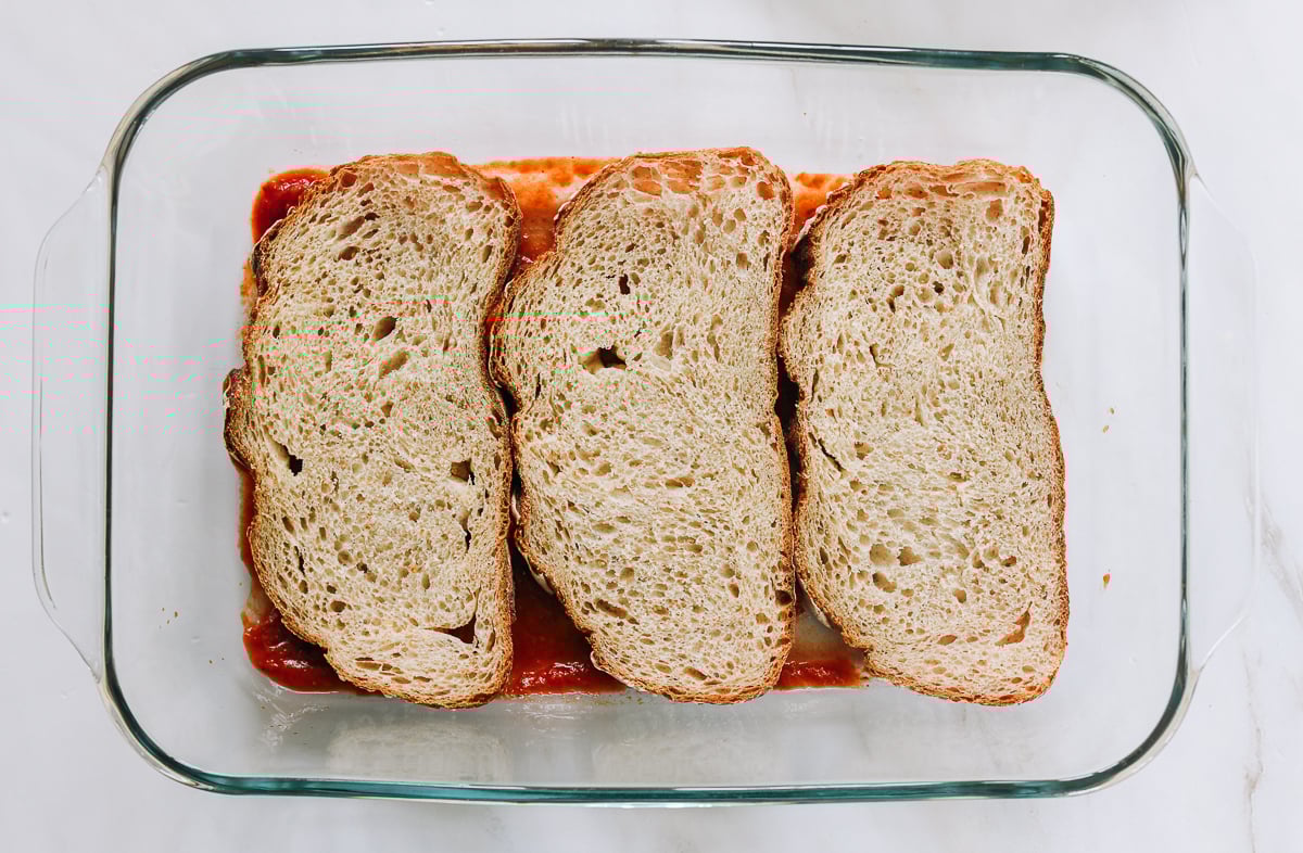 sourdough bread slices layered on top of marinara sauce