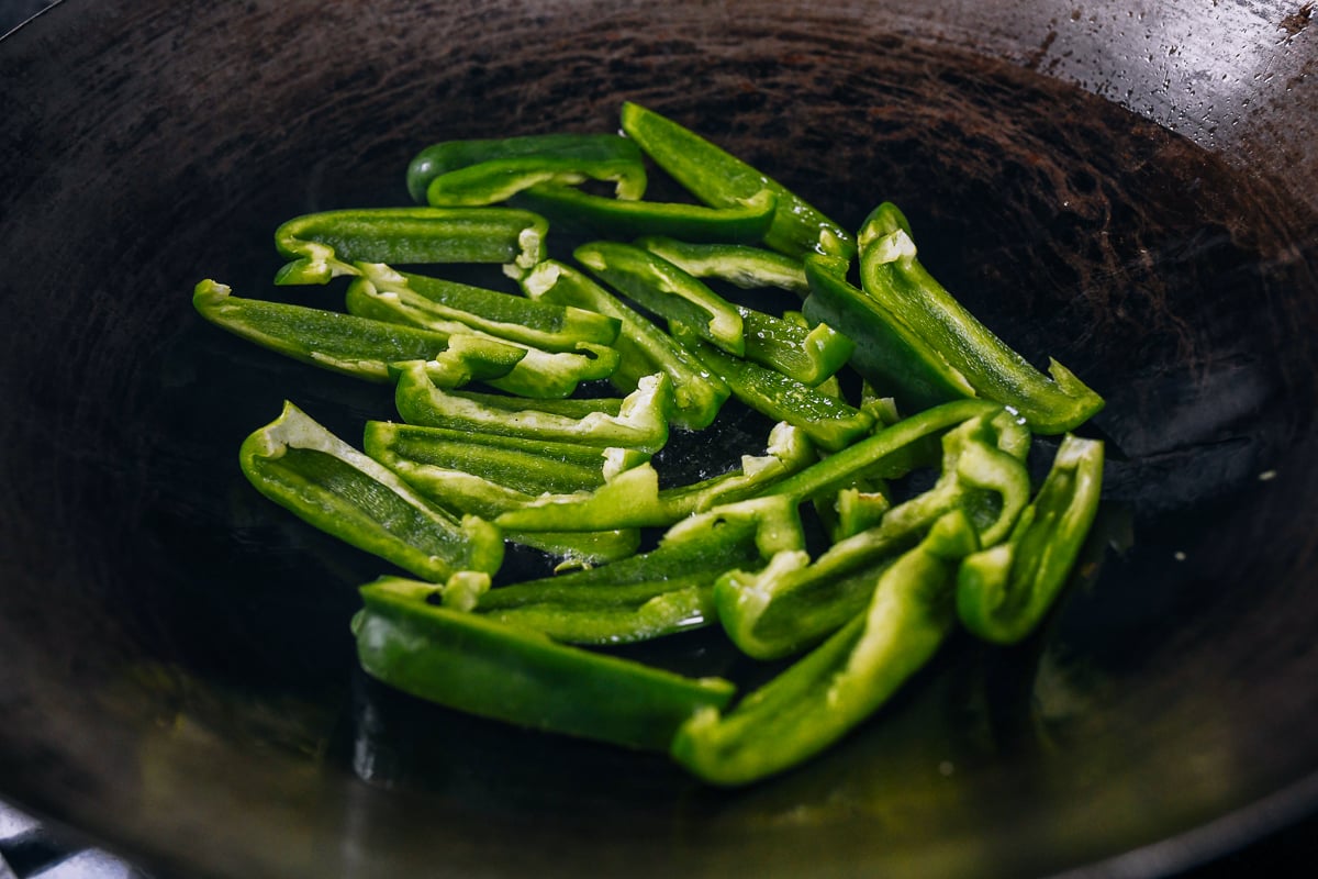 sliced green peppers in wok