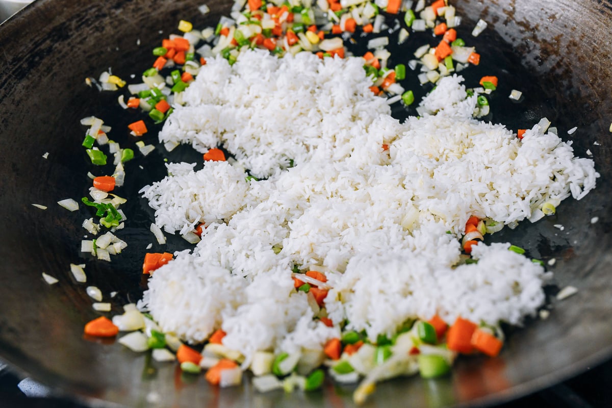 adding rice to vegetables in wok