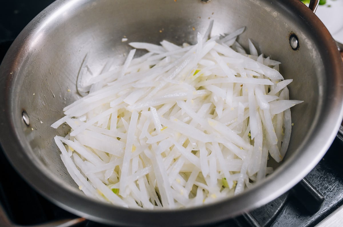 cooking julienned daikon with scallion and ginger