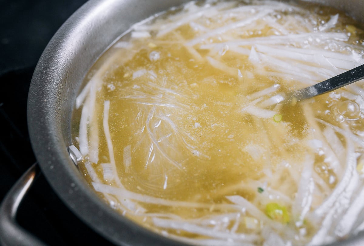 adding mung bean noodles to soup with daikon radish