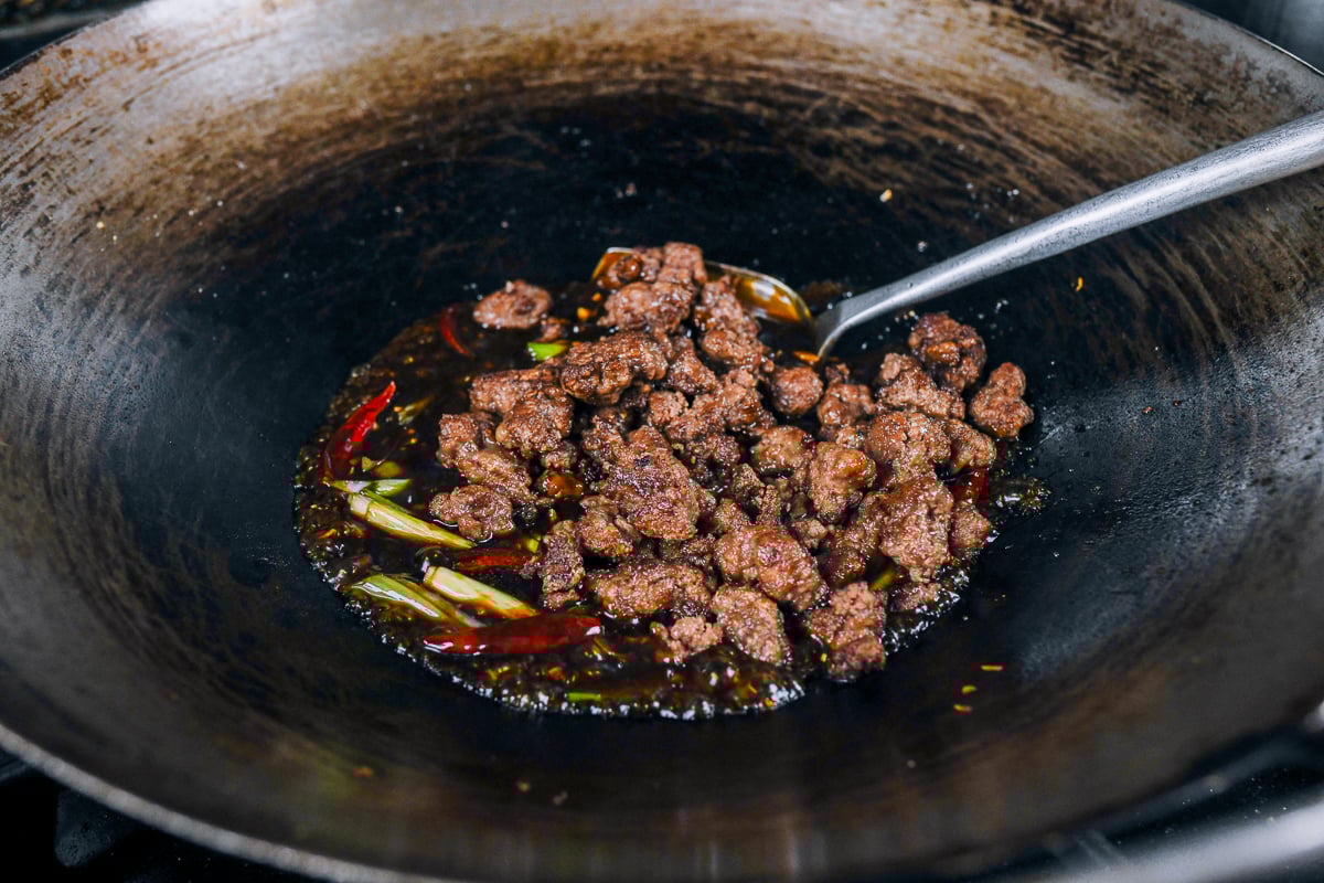 adding crispy ground beef to wok with sauce