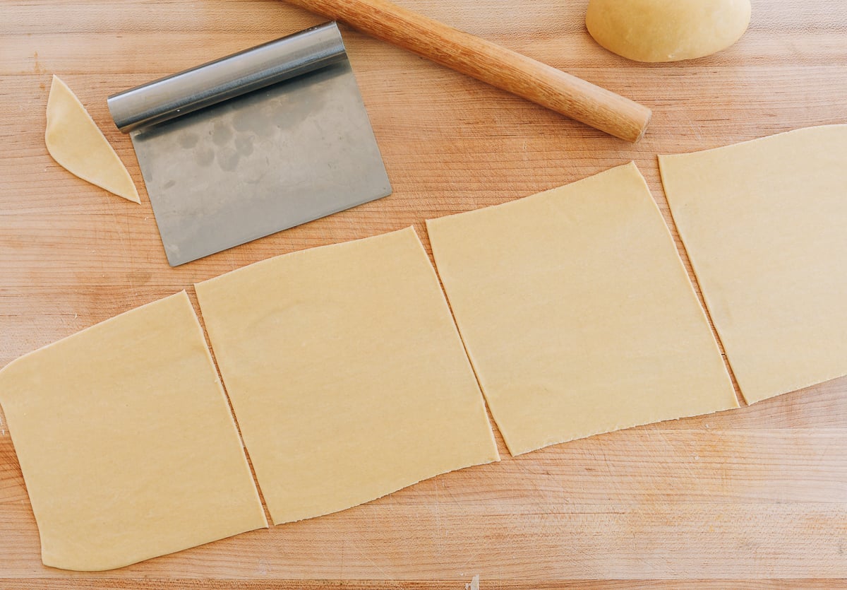 Homemade egg roll wrappers freshly cut on cutting board