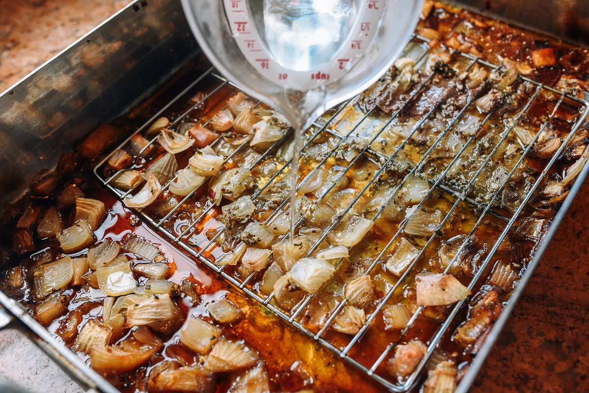 pouring water into roasting pan with onions