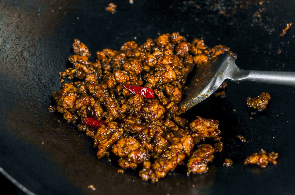 stirring general tso's ground chicken in wok with sauce