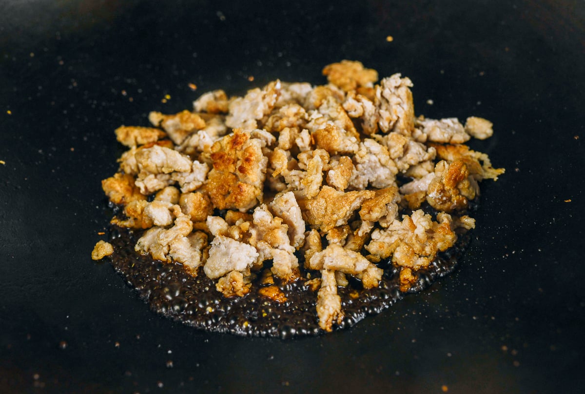 adding chicken to sauce in wok