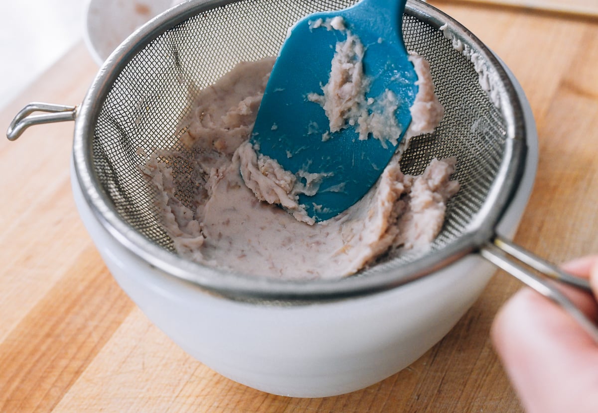 pushing steamed taro through sieve to make it smooth