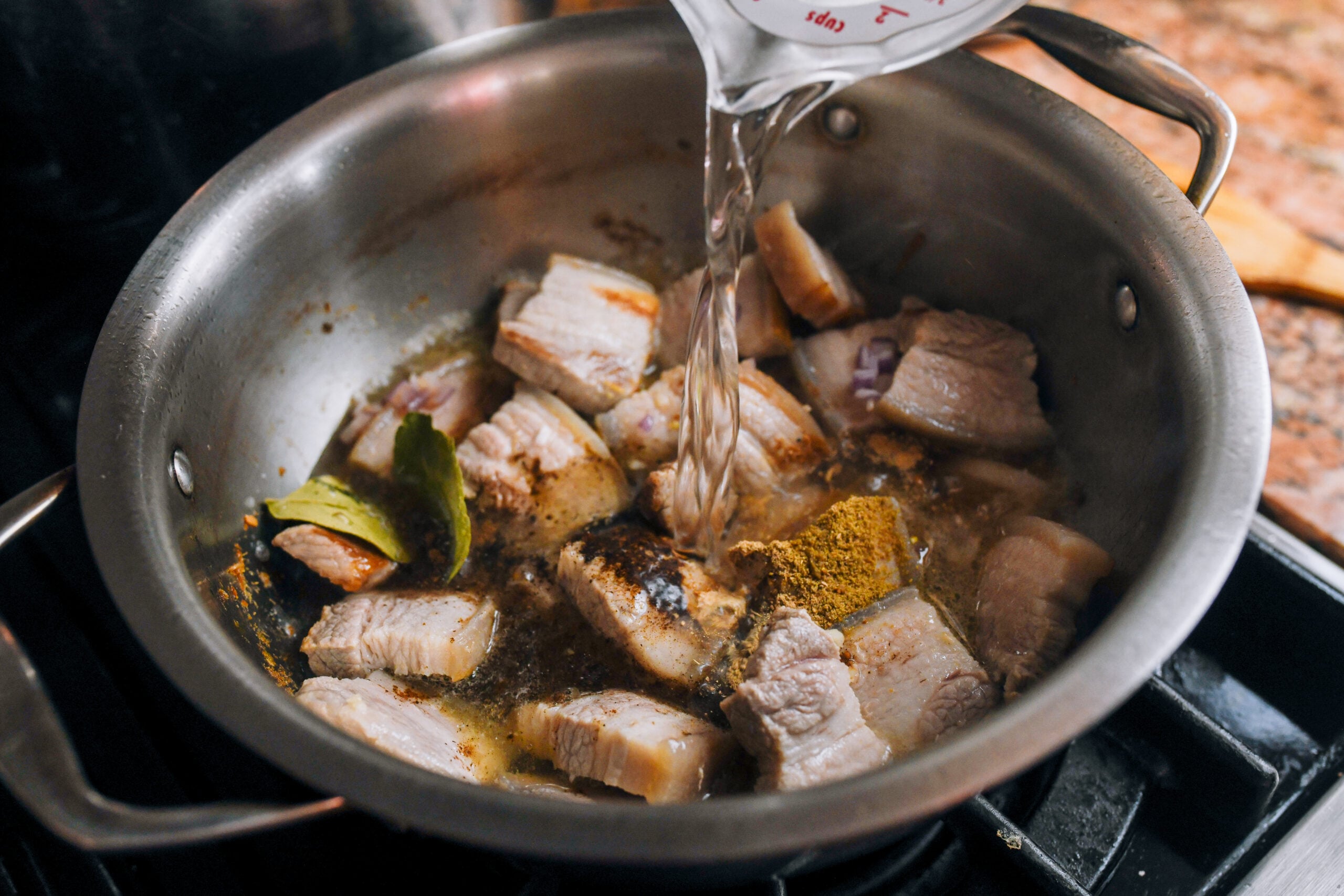 pouring water onto pork belly in pot