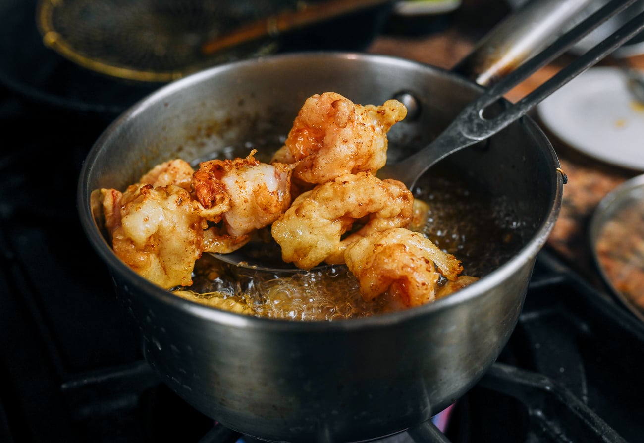 pulling fried shrimp out of hot oil using slotted spoon