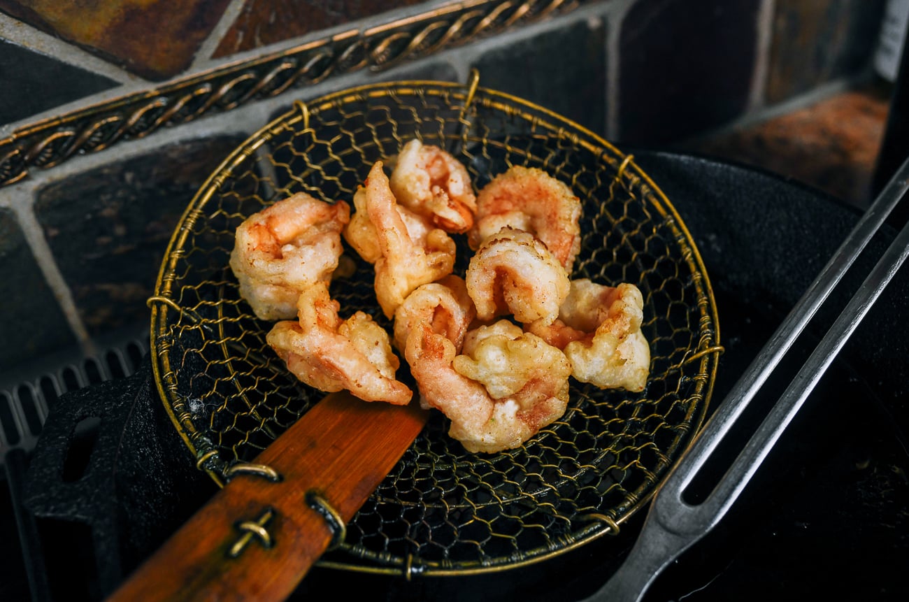 fried shrimp draining in Chinese spider strainer
