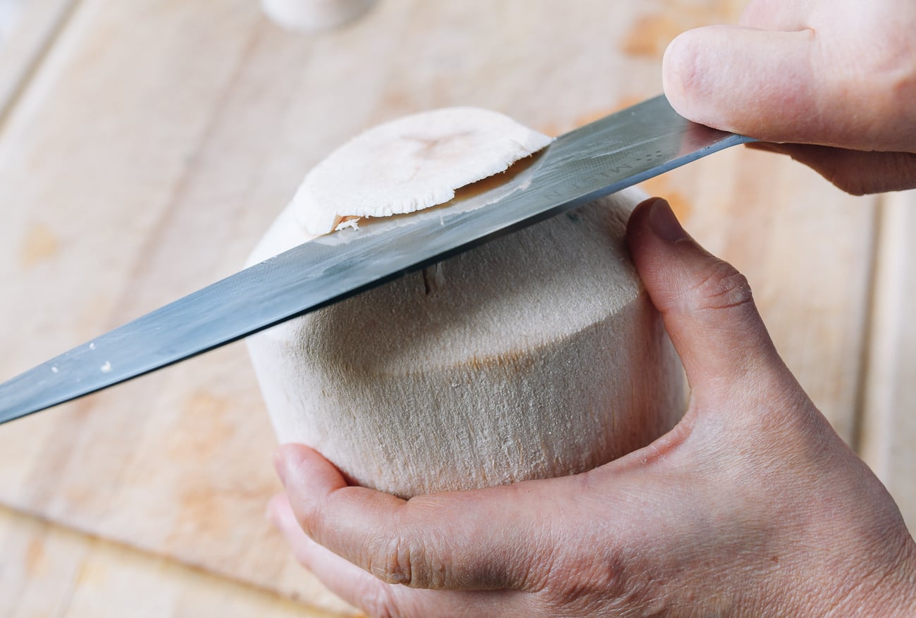 cutting top off of young coconut