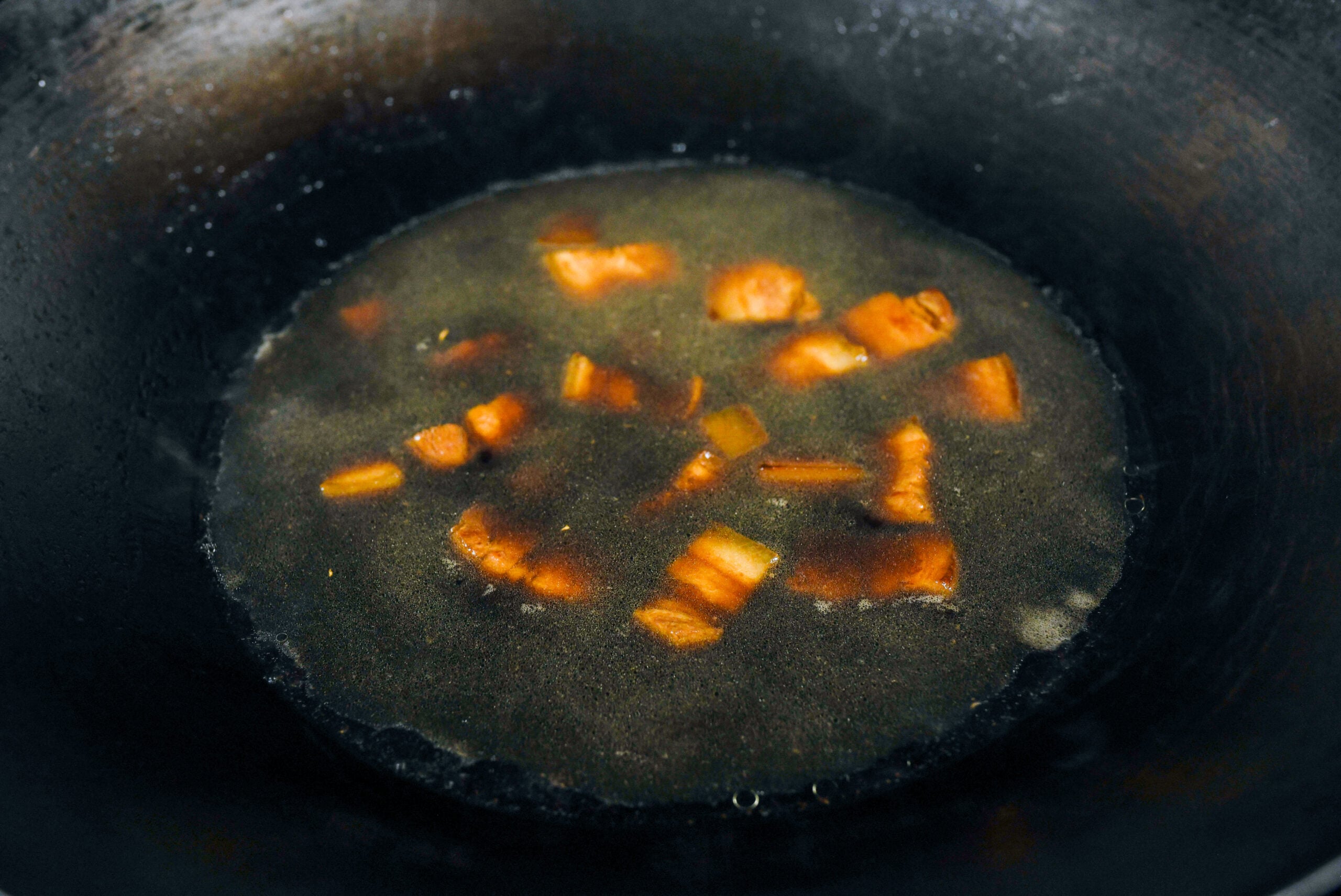 sauces and water in wok to braise pork belly