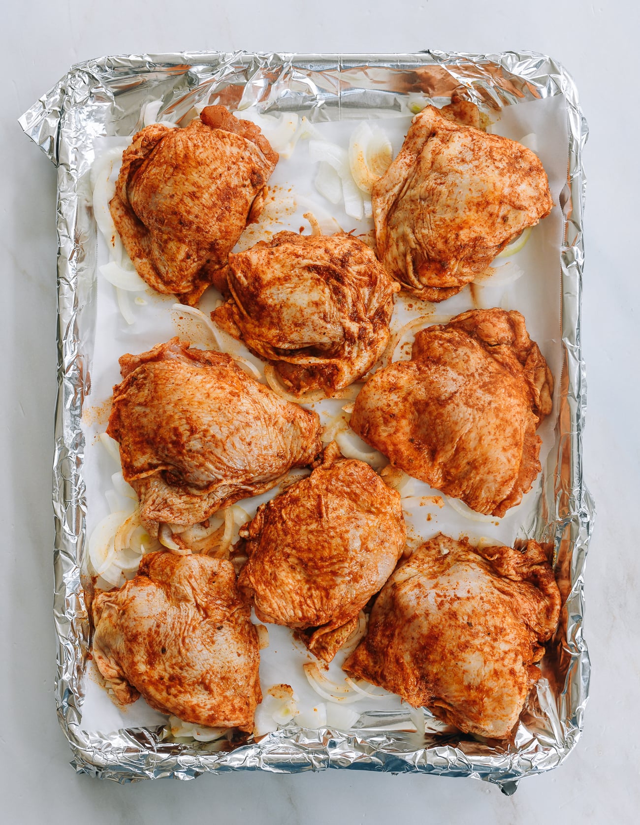 marinated chicken thighs on baking sheet with onion