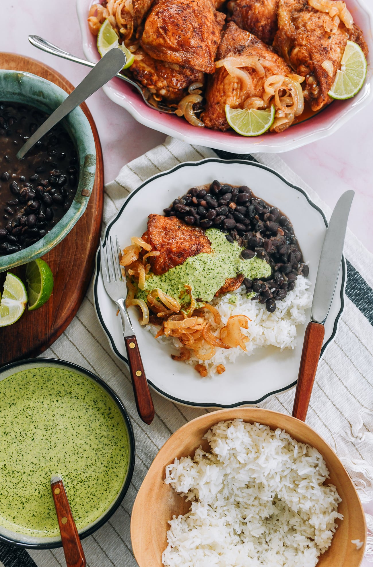 Sheet pan peruvian chicken thighs served with rice and beans and green sauce