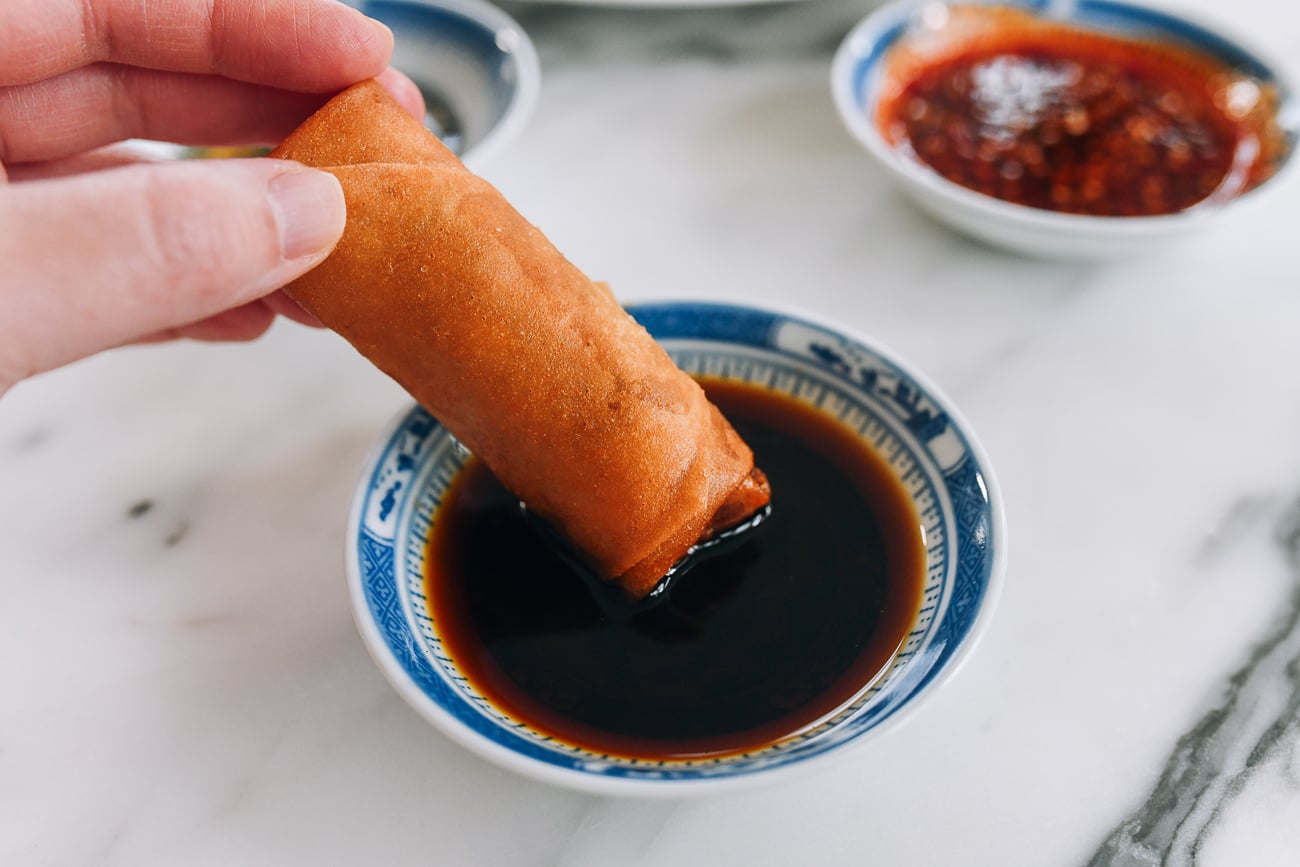 dipping spring roll into Worcestershire-based sauce