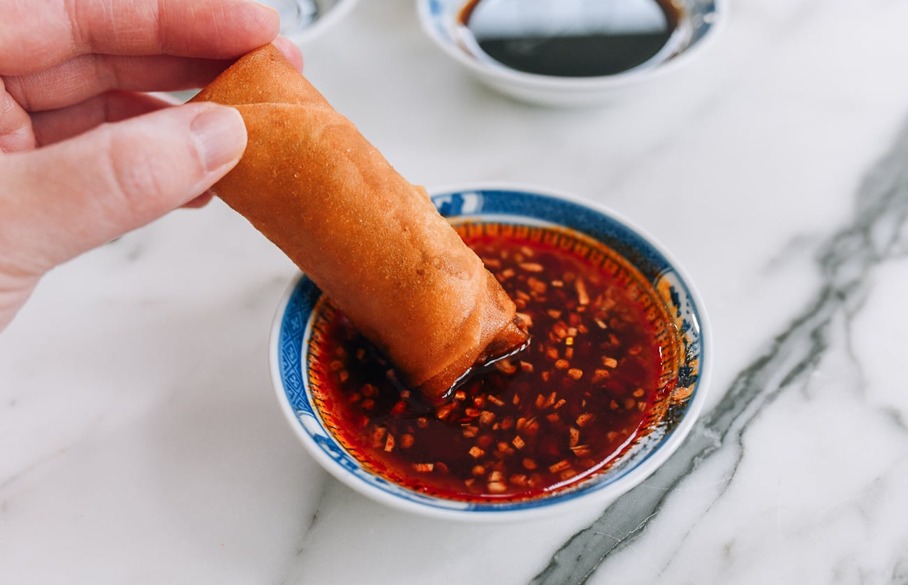 dipping spring roll into sweet chili sauce