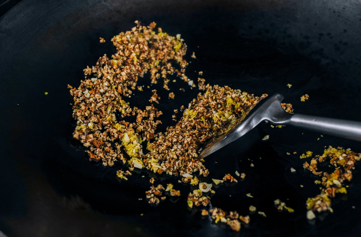 cooking finely chopped shiitake mushrooms in wok with ginger and garlic