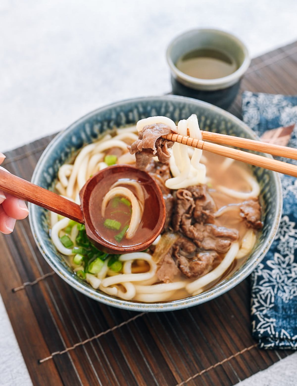 eating beef udon with chopsticks and spoon