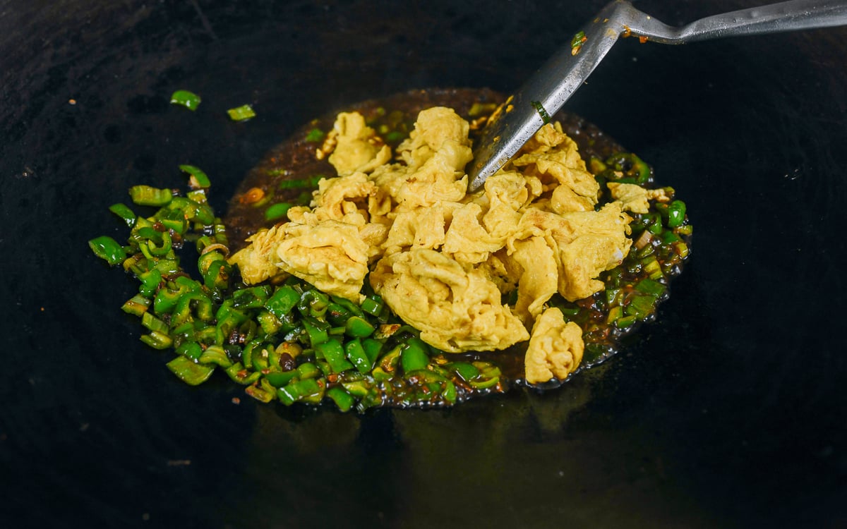 scrambled eggs added to peppers, scallions, and sauce