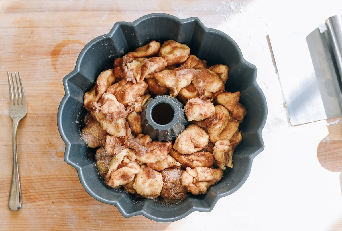 dough pieces coated in butter and cinnamon sugar and added to bundt pan