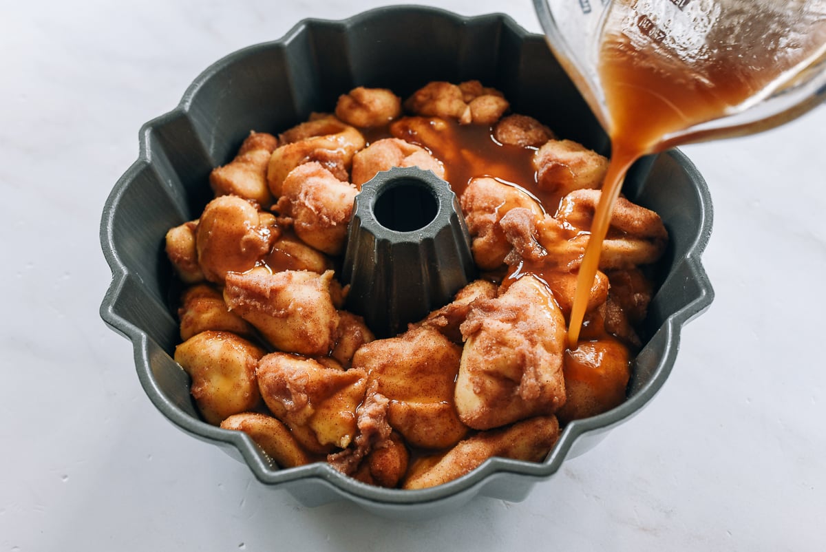 pouring butter, brown sugar, vanilla mixture over monkey bread before baking