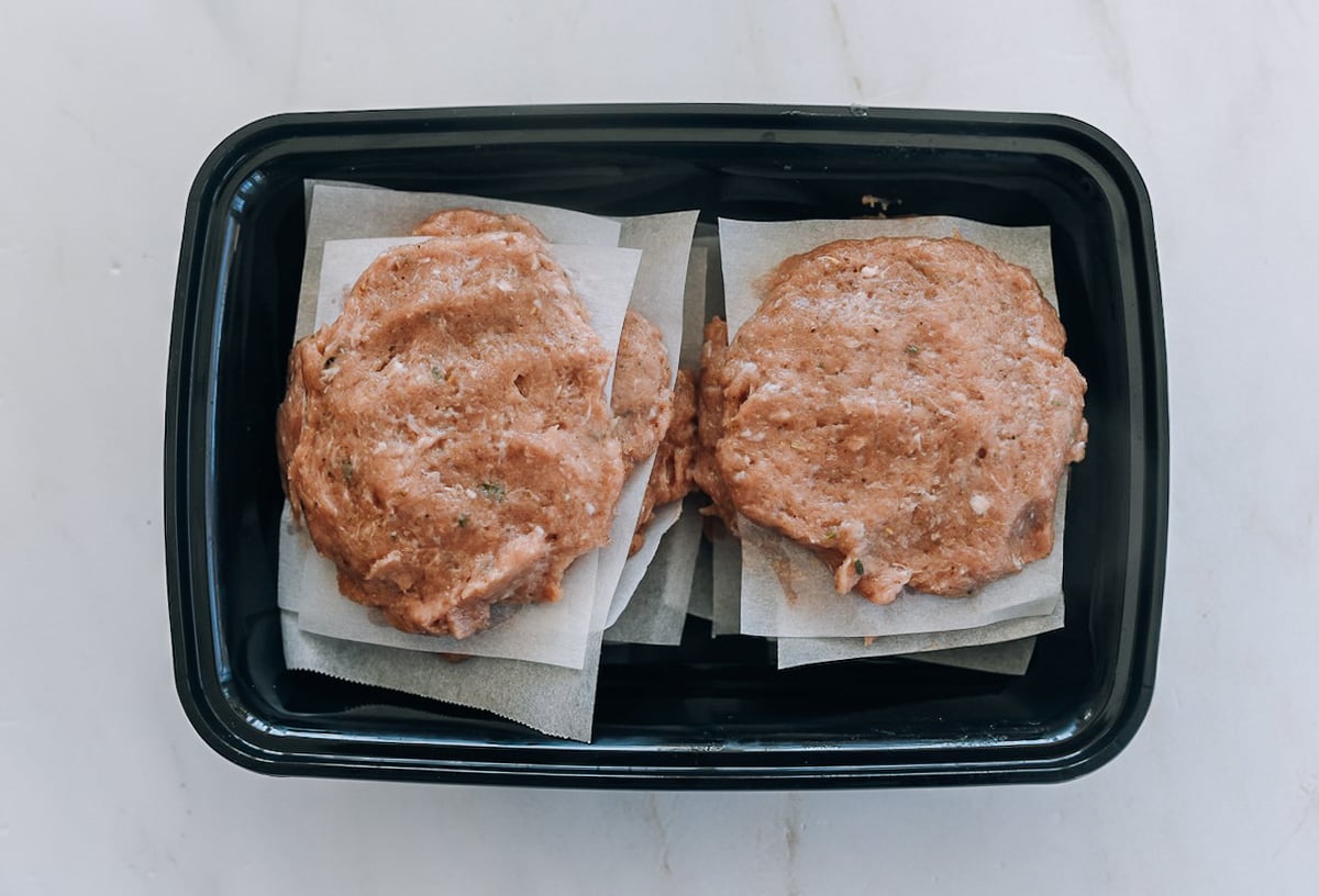 turkey sausage patties between parchment paper in a container
